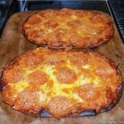 Two cooked flat bread pizzas on stone