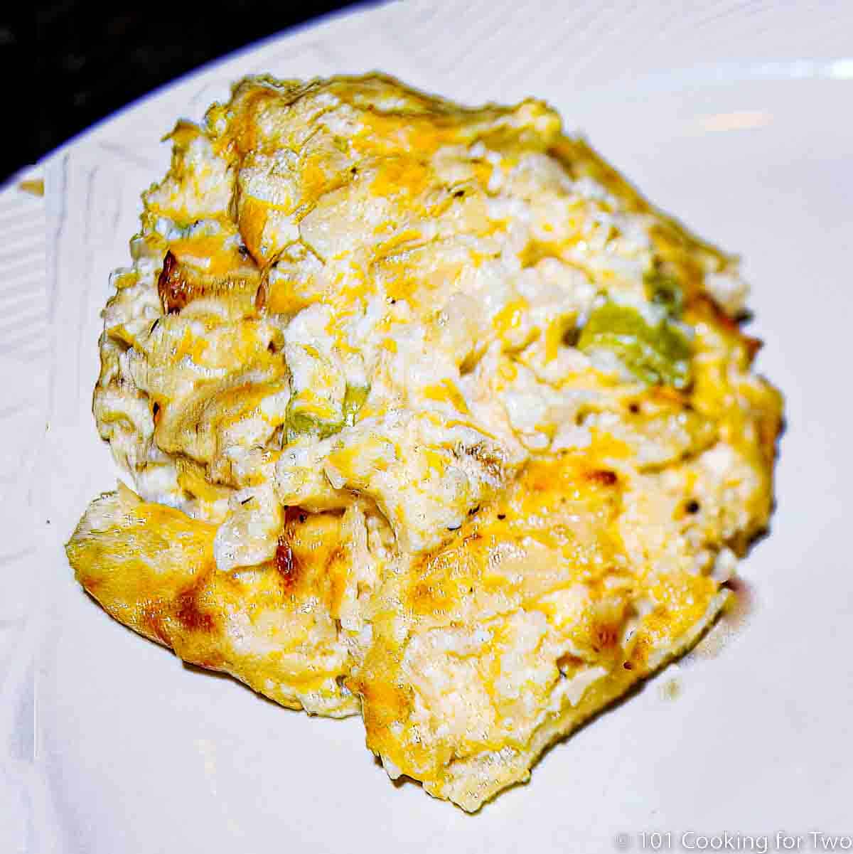 cheesy cauliflower casserole on white plate.