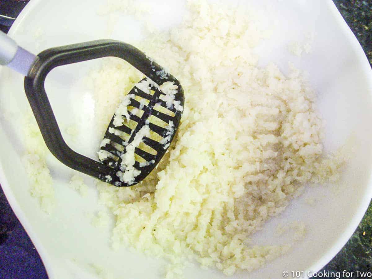 mashiing cauliflower with potato masher