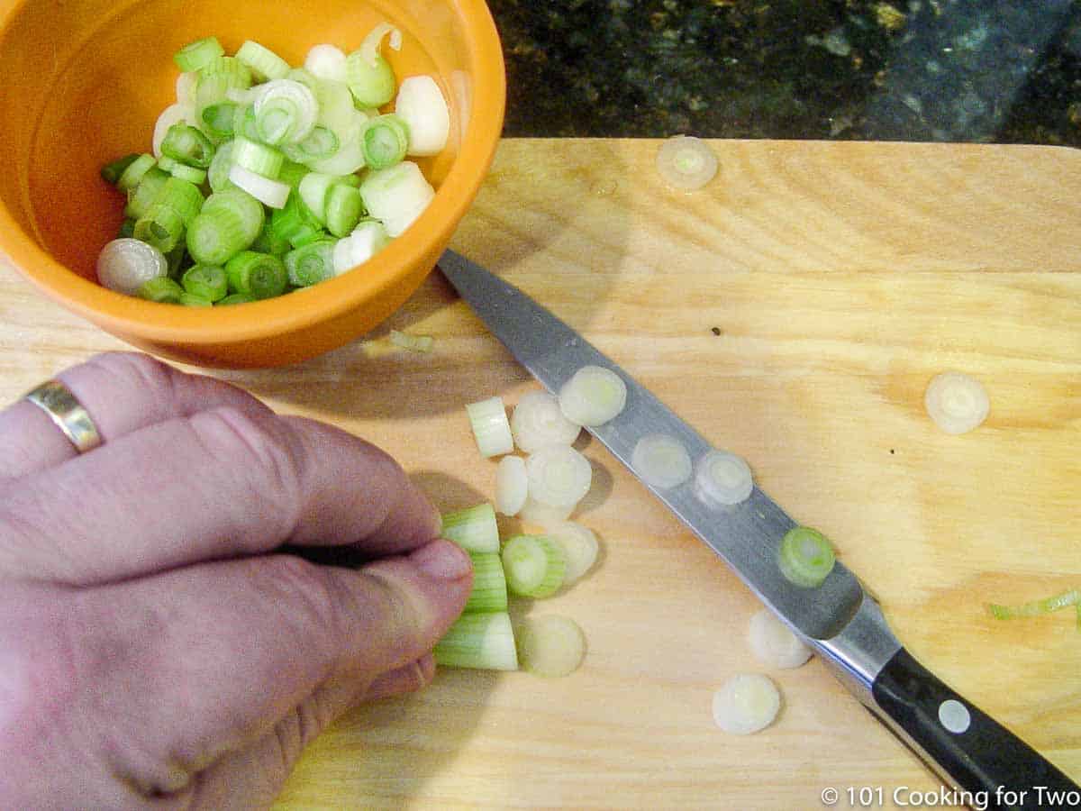 slicing green onion on wooden board.