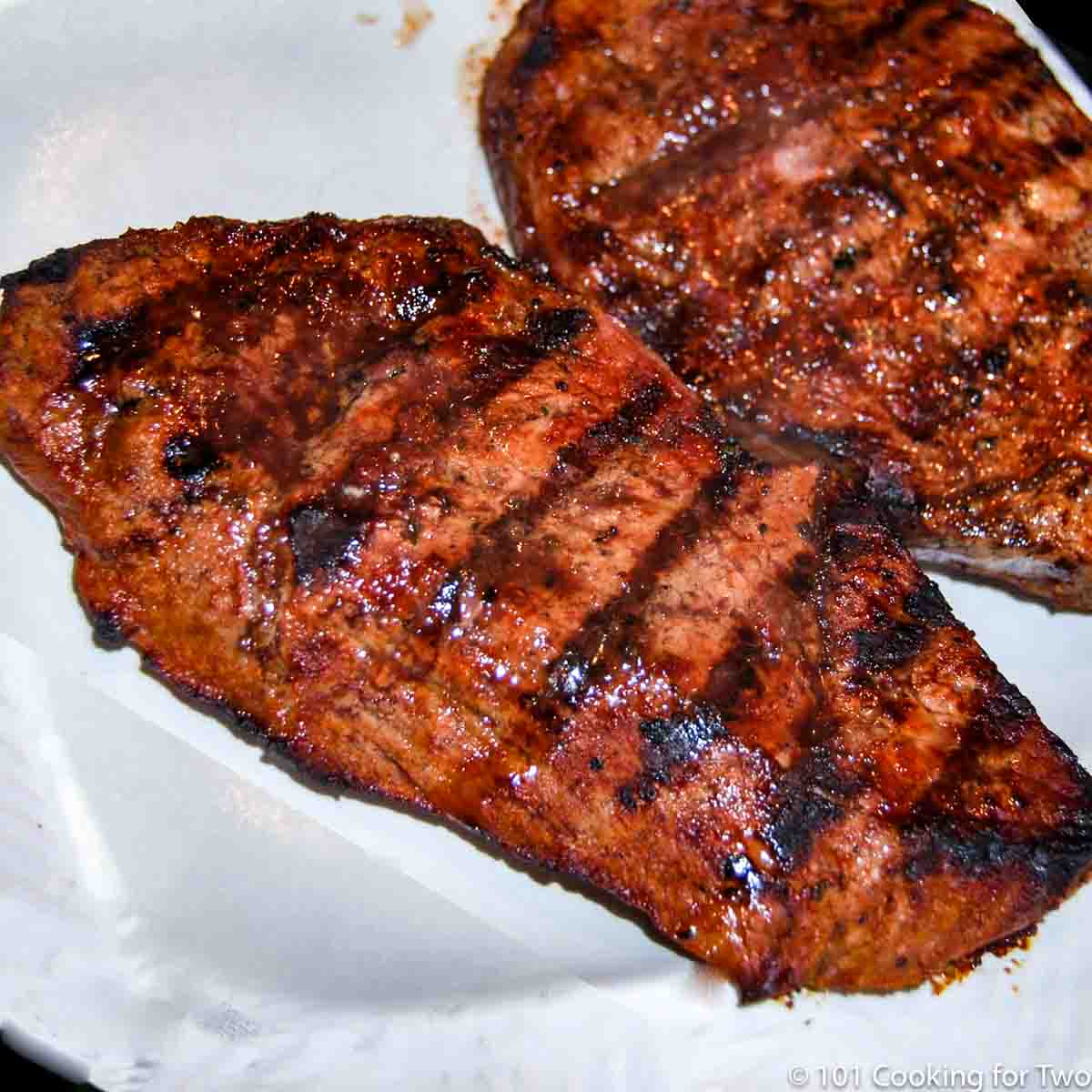 Grilled marinated sirloin steak on a white plate.