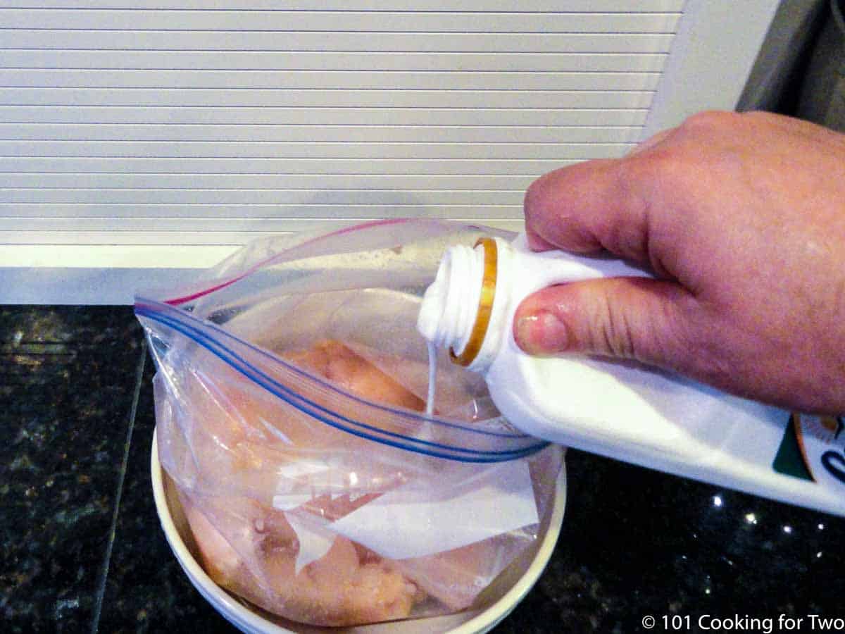 adding buttermilk to bag with raw chicken.