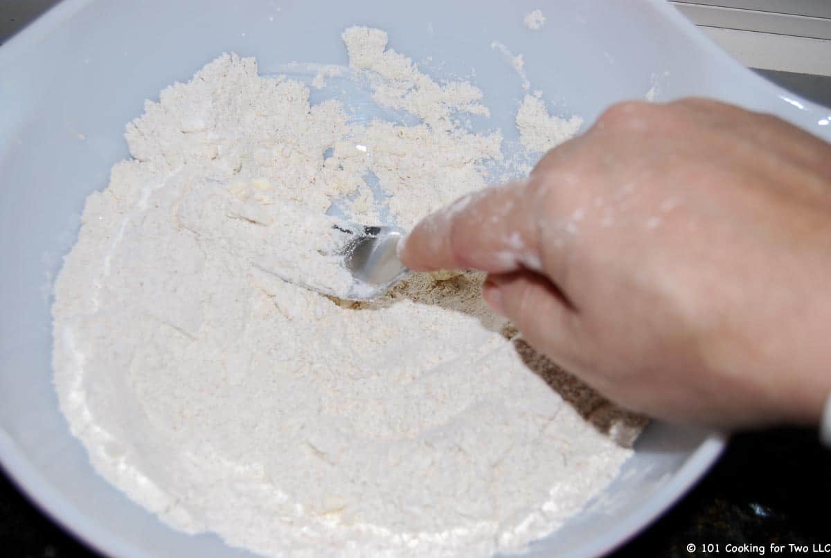 cutting butter into a bowl of flour with fork.