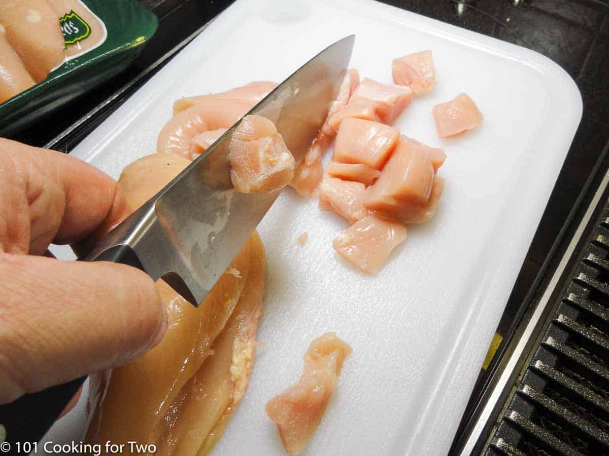 cutting skinless chicken into cubes.
