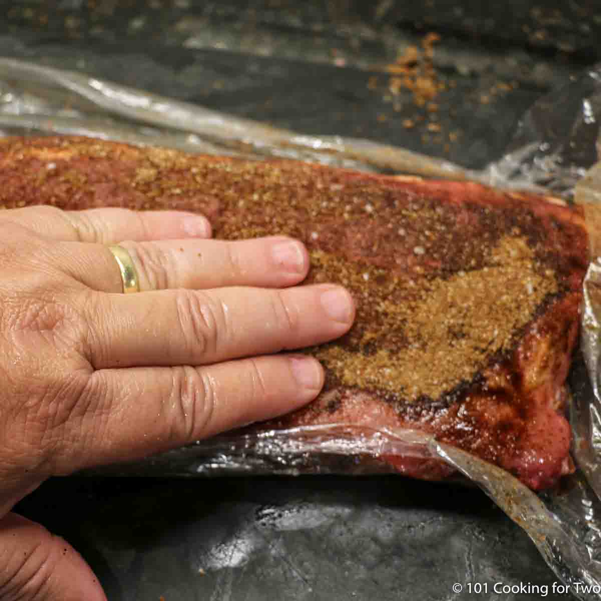 Applying Memphis dry rub to baby back ribs.