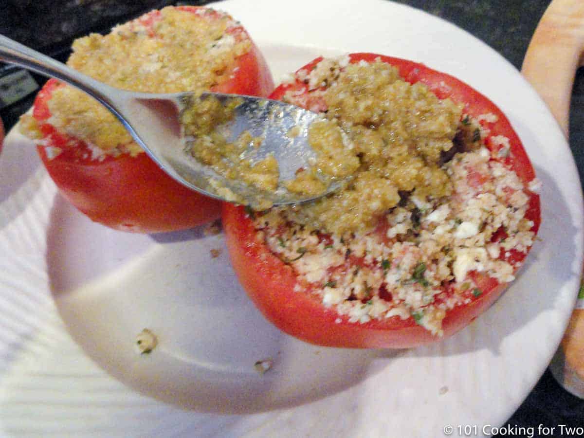 adding topping to stuffed tomatoes.