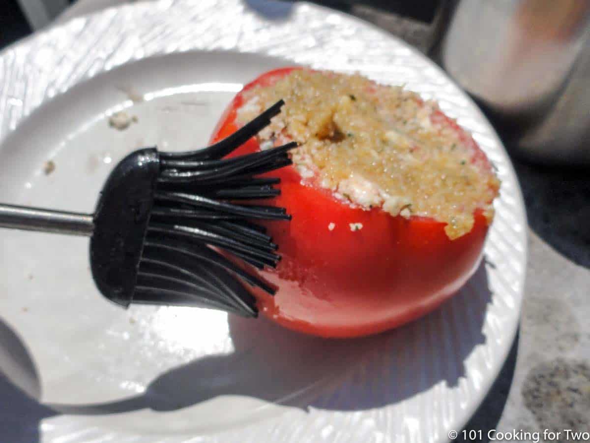 brush tomatoes with oil on white plate.