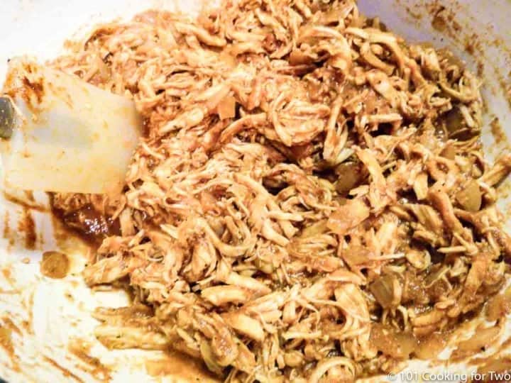mixing shredded chicken with seasoning