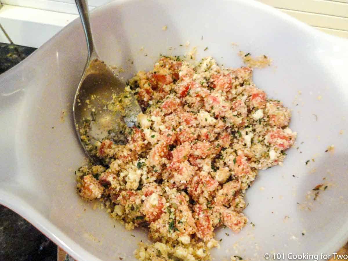 mixing stuffing for tomatoes in white bowl