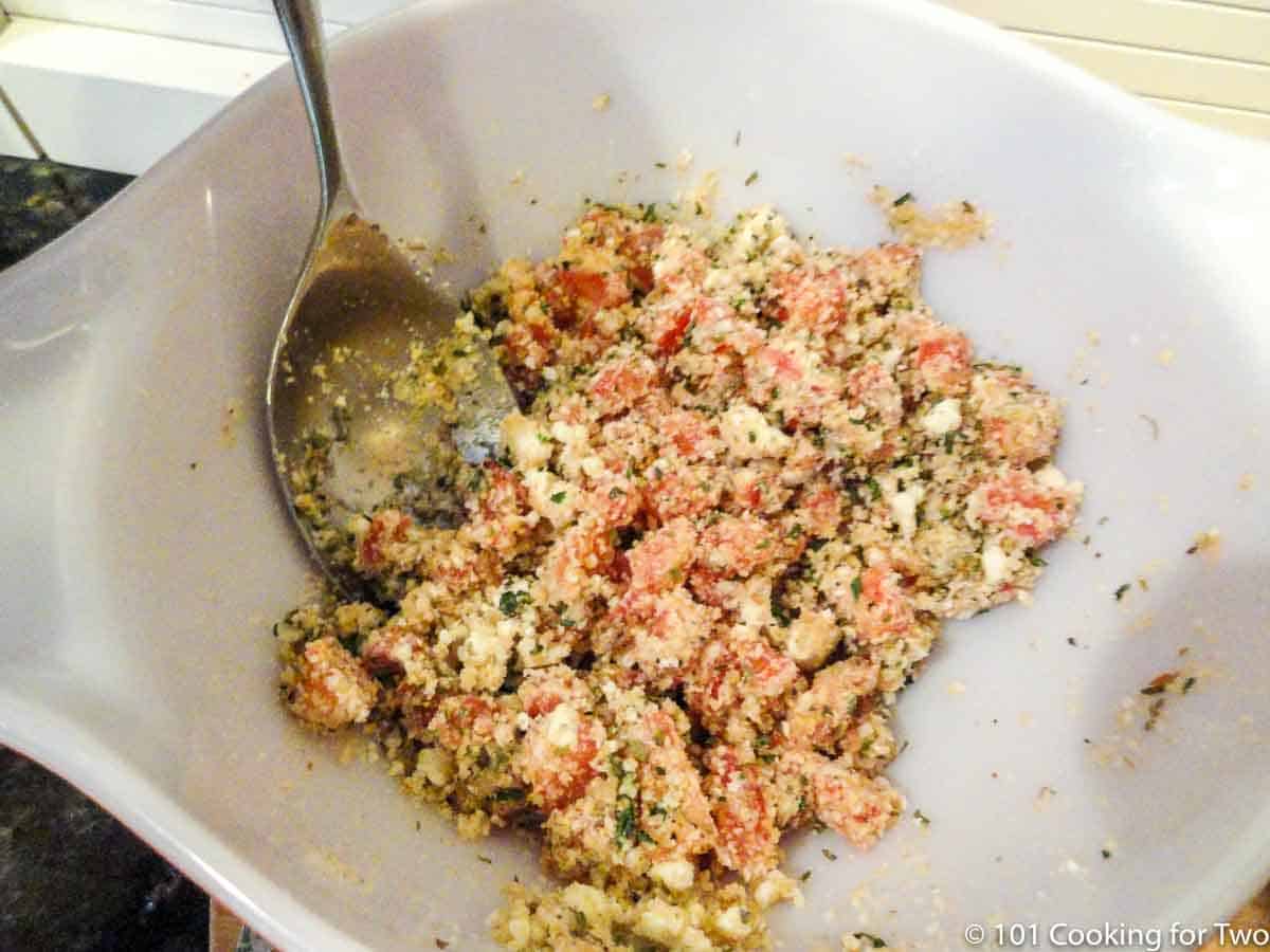 mixing stuffing for tomatoes in white bowl.