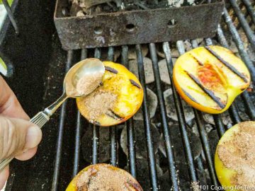 spooning sugar mixture on partly grilled peach half
