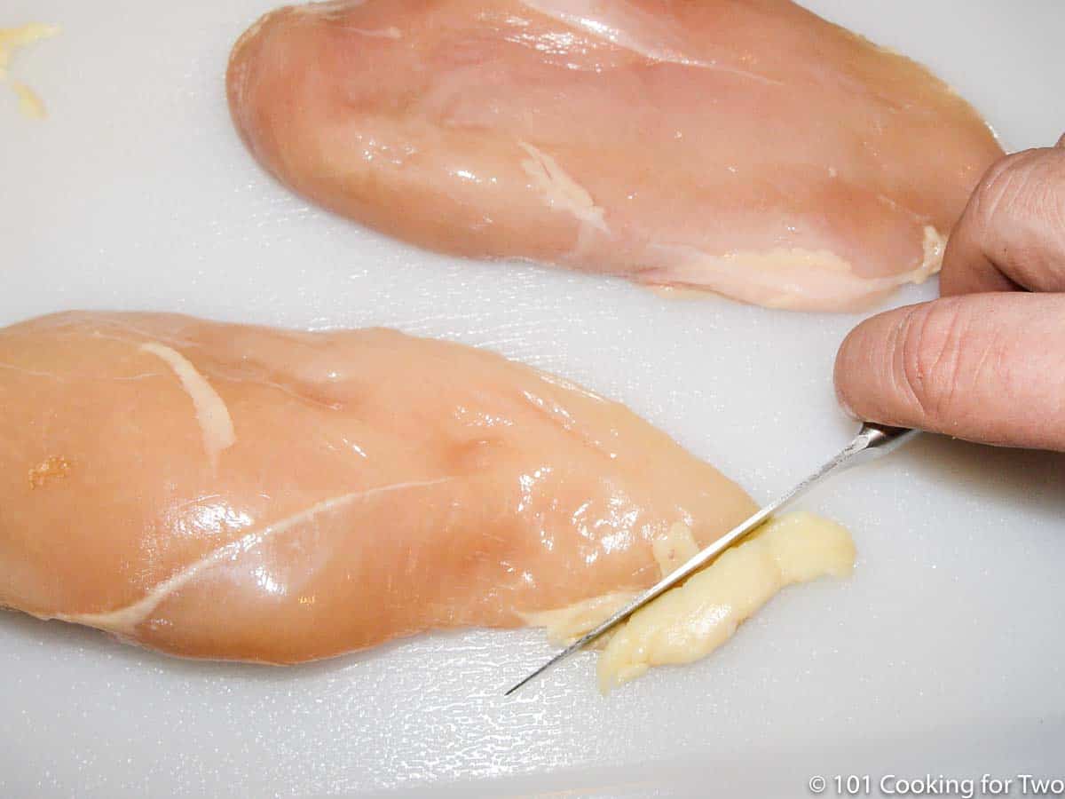 trimming chicken breasts on a white board.