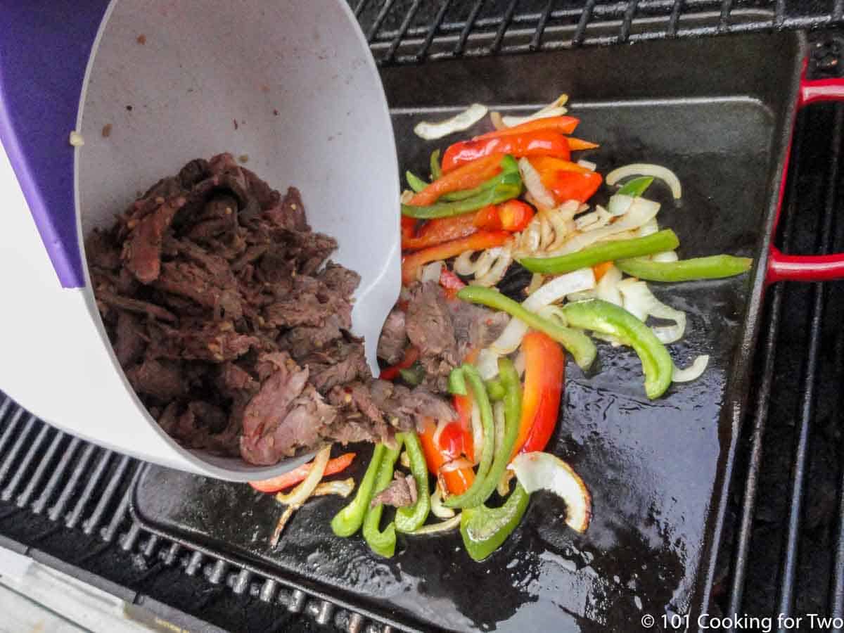 adding beef to griddle with veggies.