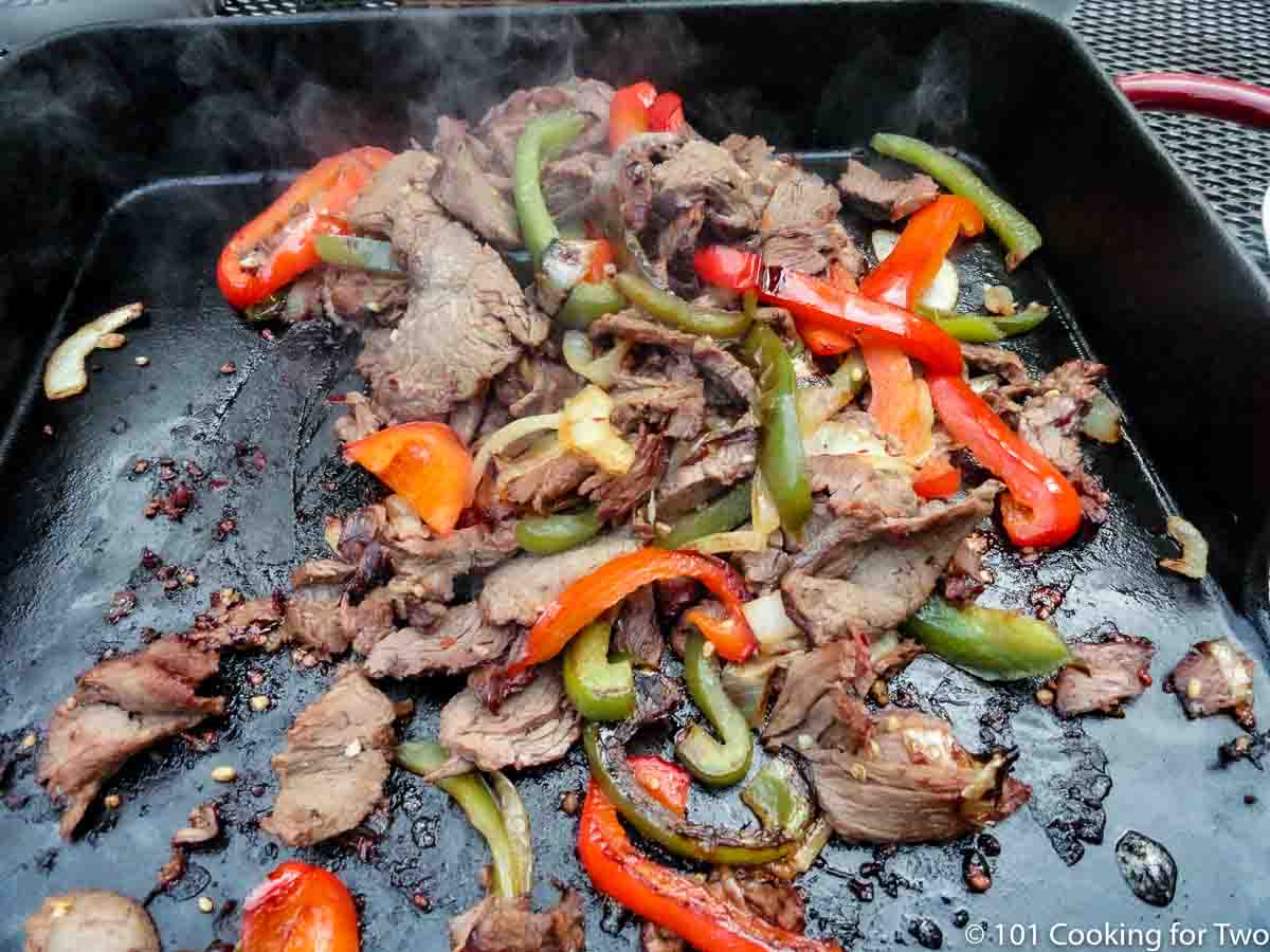 cooked meat and vegetables on griddle.