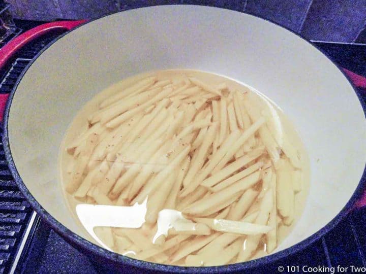 raw fries in oil in Dutch oven