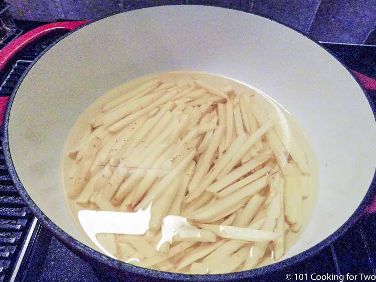 raw fries in oil in Dutch oven.