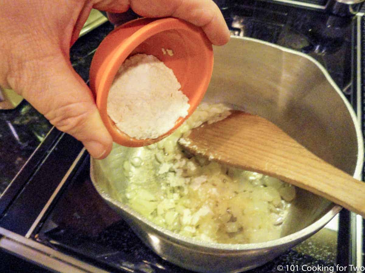 adding flour to cooked onion and butter in saucepan