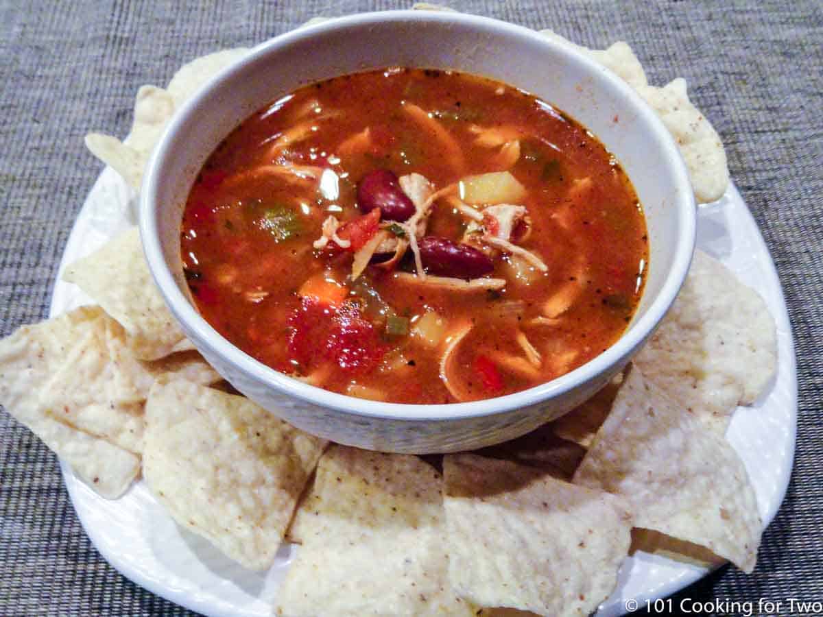 chicken chili in white bowl with chips.
