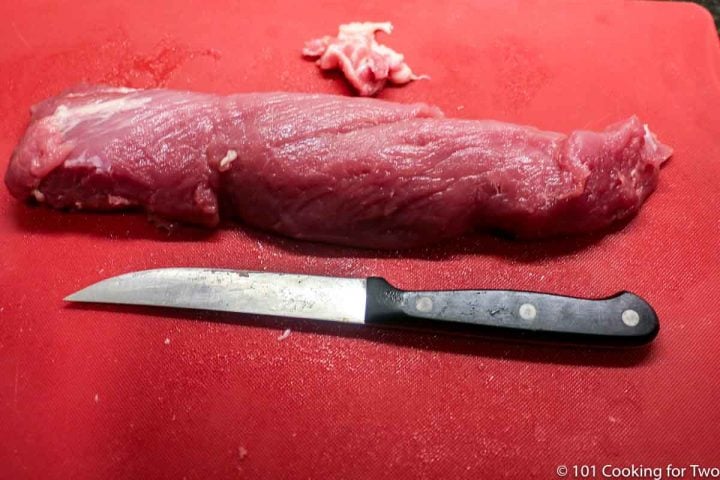 Trimmed pork tenderloin on red board