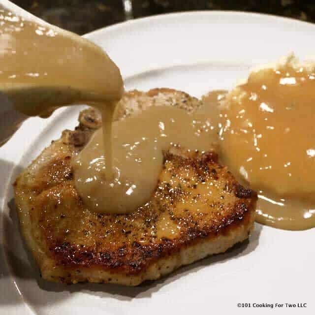 image of pouring gravy over a pork chop on a white plate.