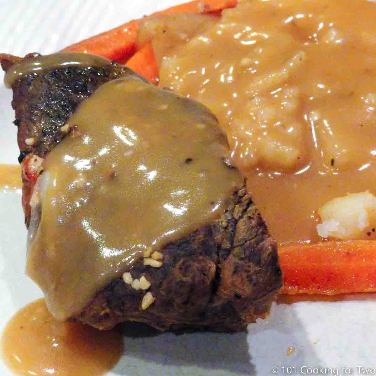 Yankee pot roast on plate with potatoes and gravy.