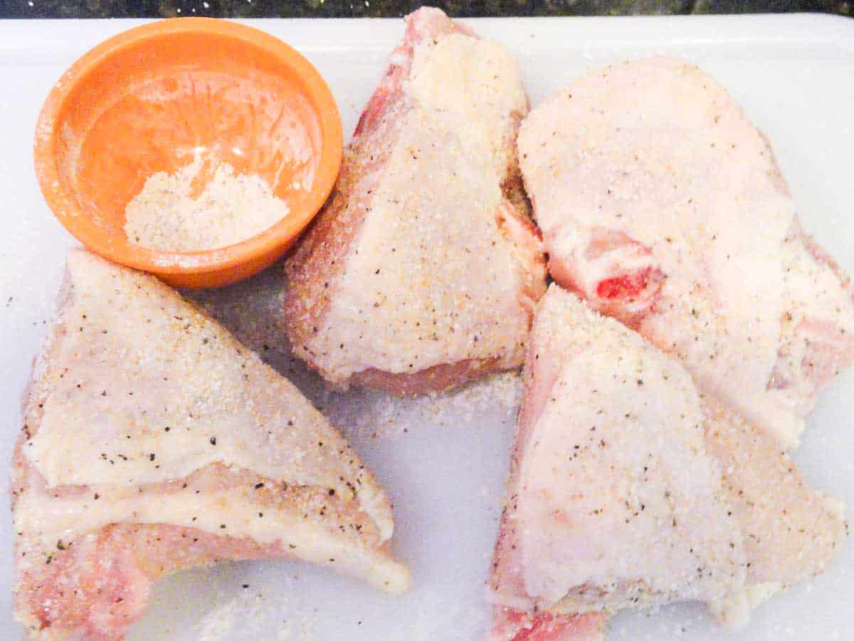 cut chicken breasts with seononing on white board.