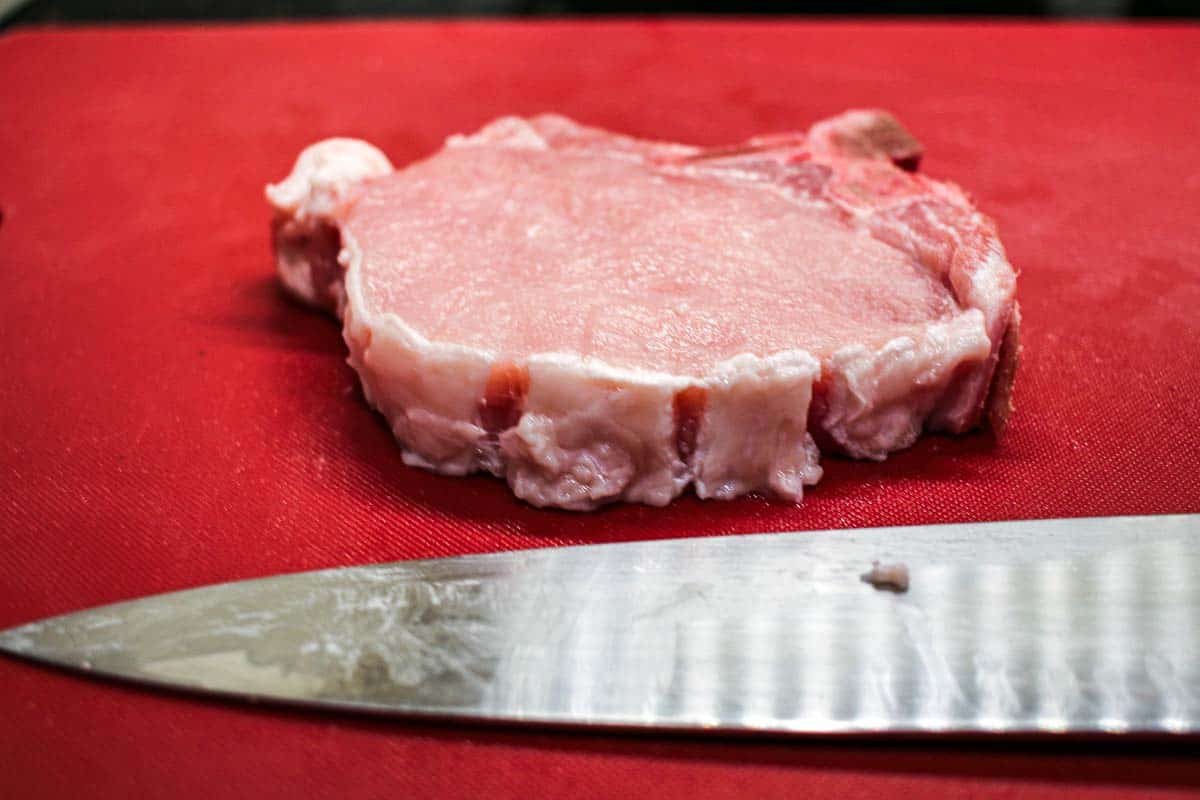 trimmed pork chop on red board