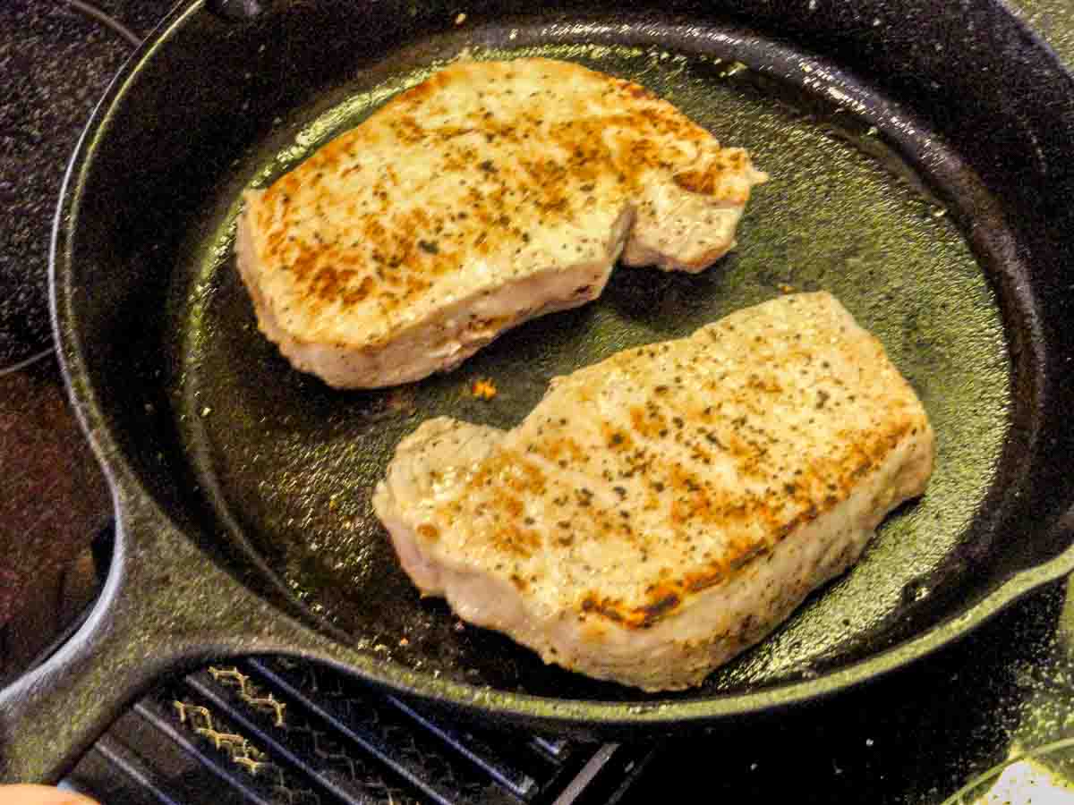 two pork chops in cast iron pan seared