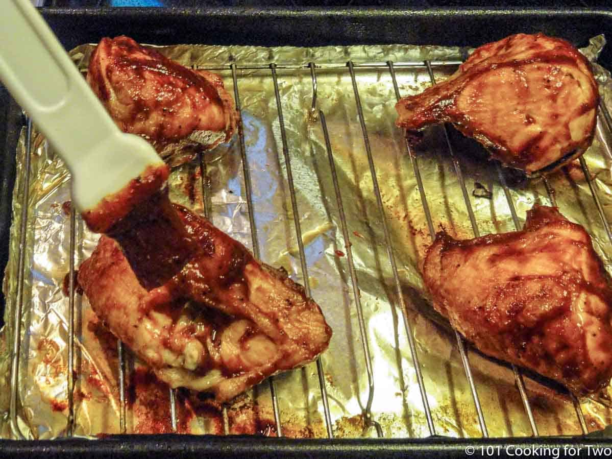 brushing sauce on cooked chicken.