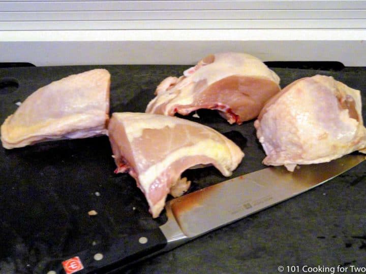 trimmed chicken breasts on black board