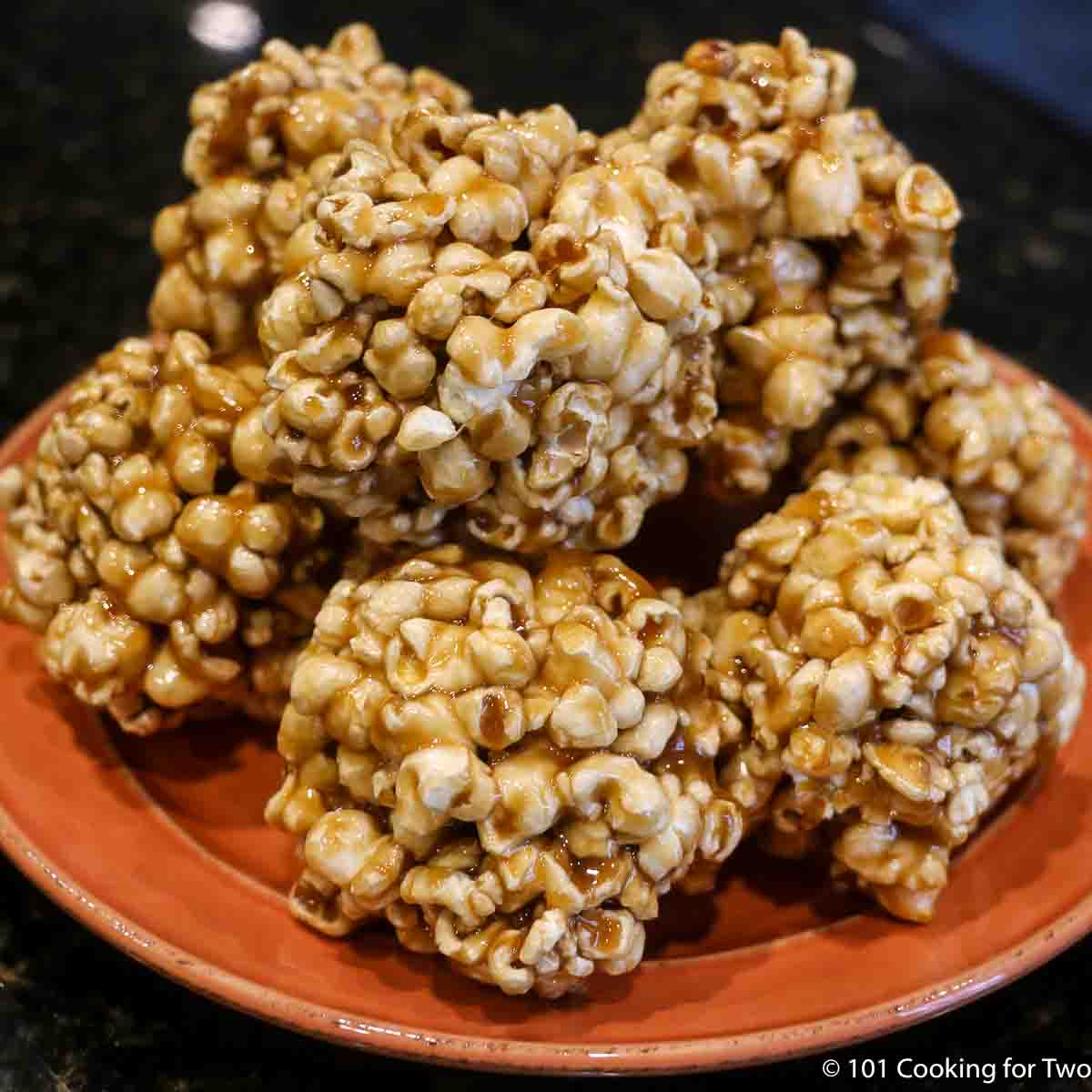 A pile of Popcorn Balls on an orange plate.
