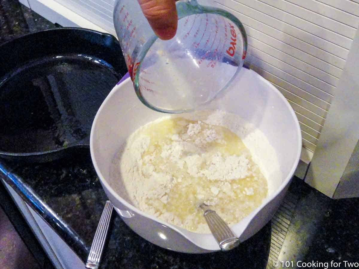 adding liquid mixture to flour mixture in white bowl.