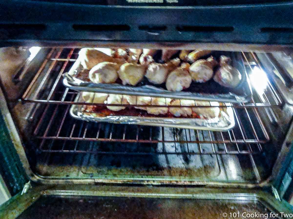 Two trays of chicken in the oven.