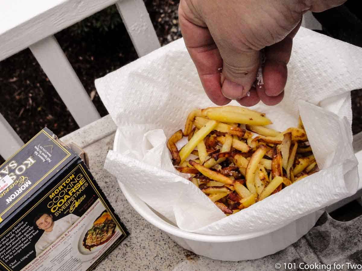 adding salt to fries in bowl