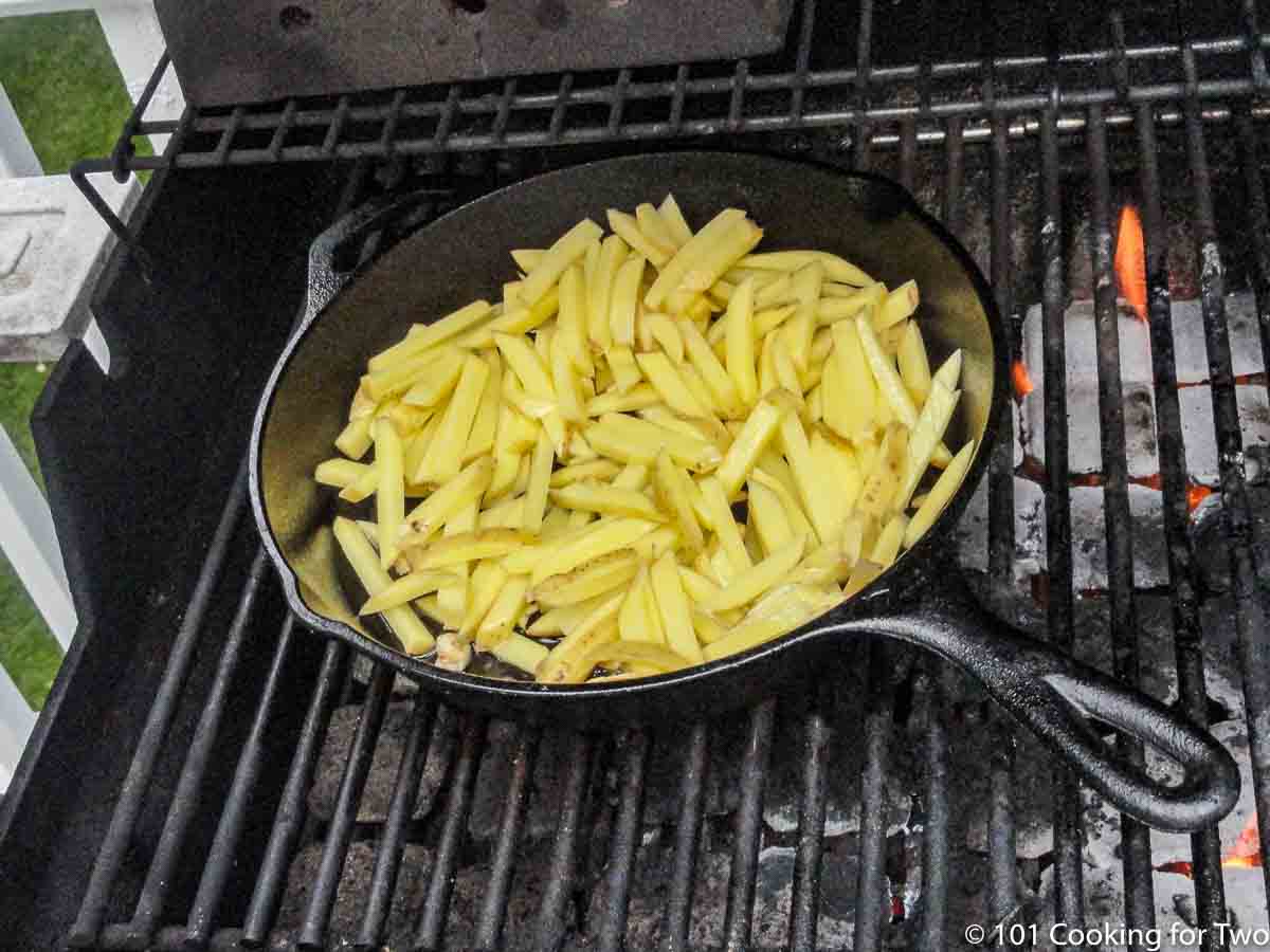 cast iron pan with fries over direct heat