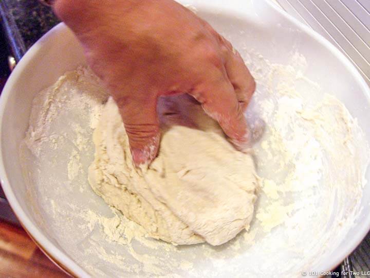 hand kneeding dough in bowl