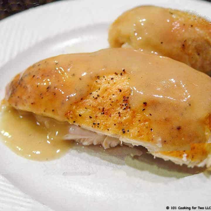 roasted chicken with gravy on a white plate
