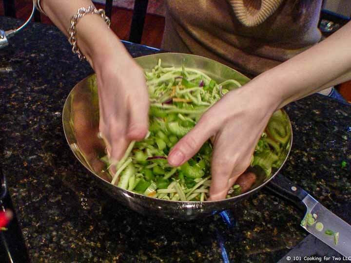 mixing veggies in bowl by hand.