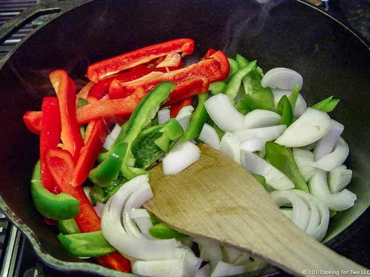 sliced peppers and onion in frying pan.