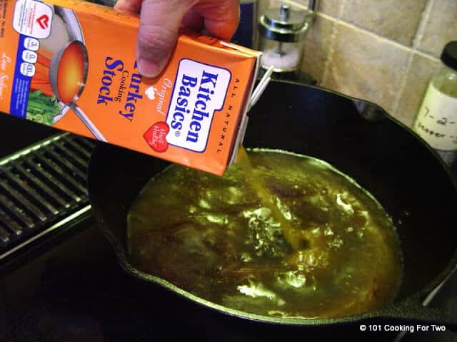 image of adding broth to a black cast iron pan