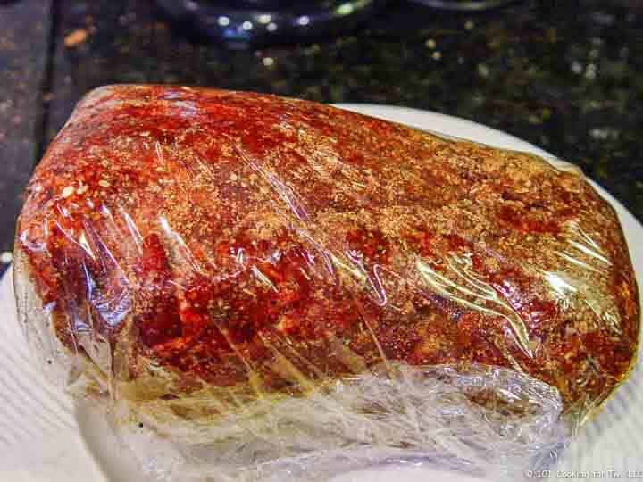pork butt wrapped with plastic with rub