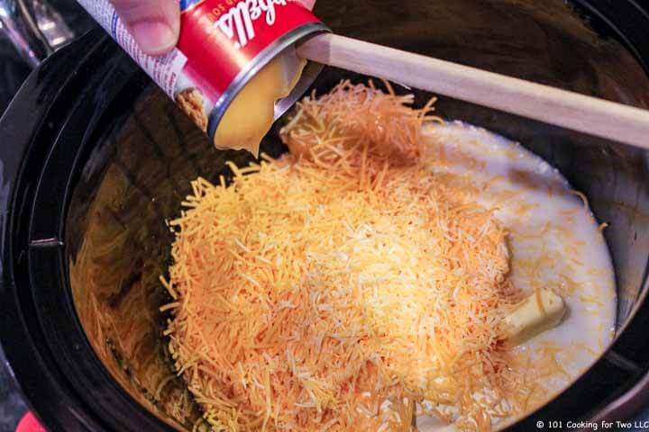 adding soup to crock pot with cheese and milk