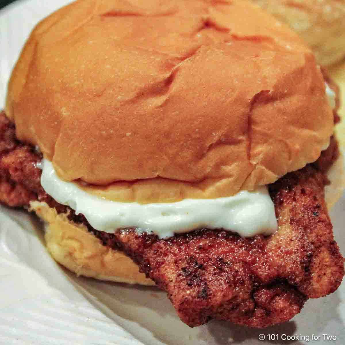 Fried pork tenderloin sandwich with mayo on a bun.