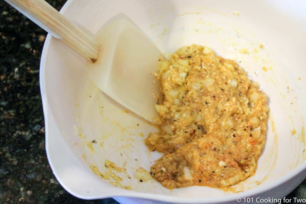 mixing eggs with bread crumbs and other ingredients in white bowl