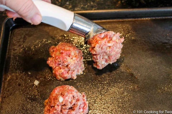 placing meatballs on tray with scoop