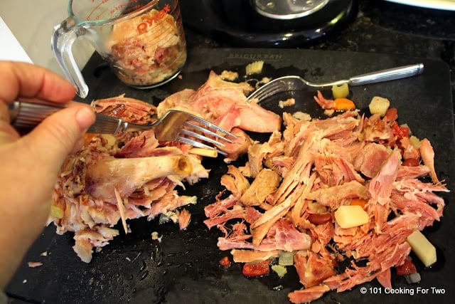 image of removing meat from the ham bone on a black chopping board