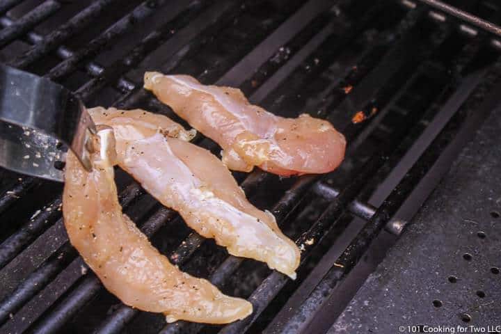 placing chicken tenders on a grill