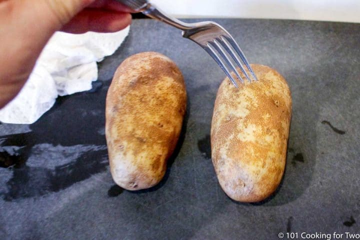 poking a potato with a fork on a black board.