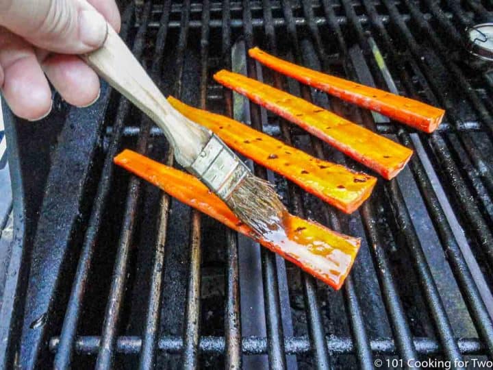brushing carrots on the grill with honey