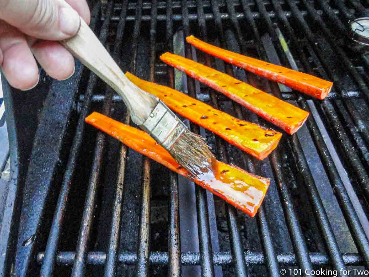 brushing carrots on the grill with honey.